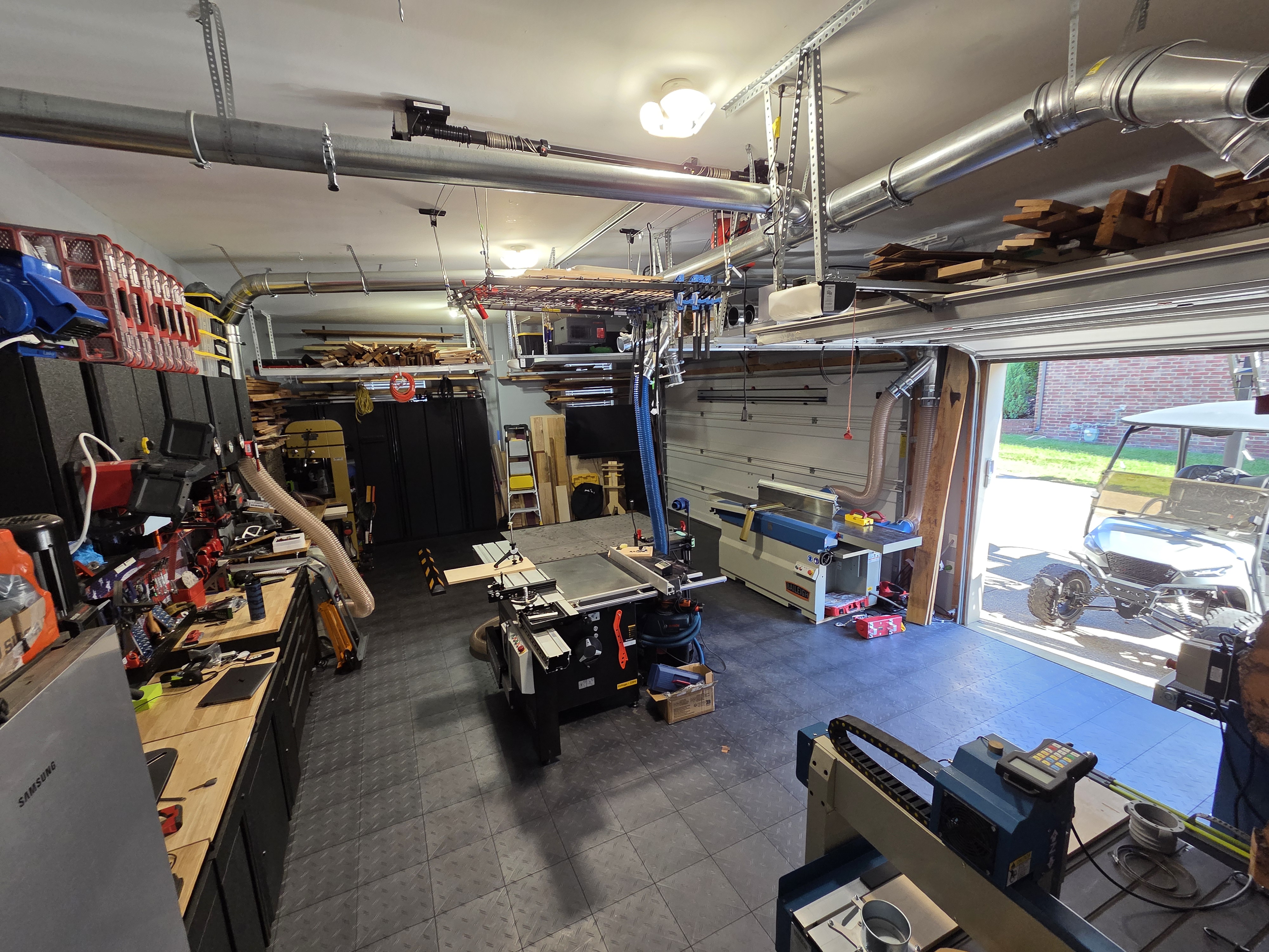 Downing Woodworks Workshop looking out toward bay door showing sliding table saw and jointer